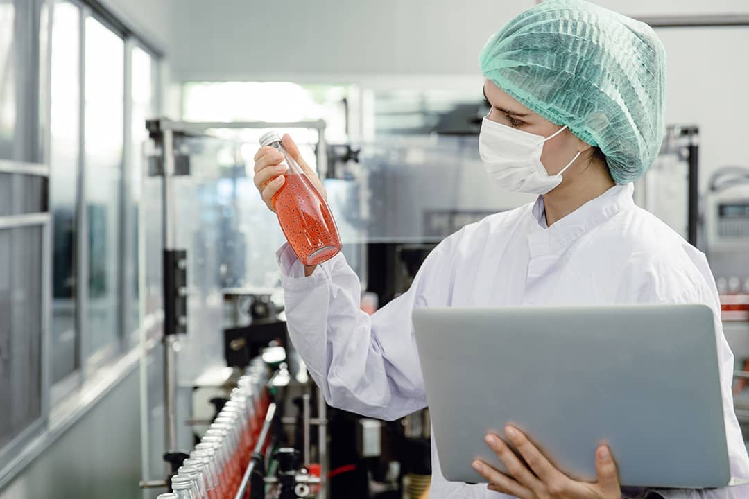 A food inspector specialist checking a bottle drink's mix and seal during the final stages of production in a factory.